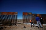 a-worker-chats-with-residents-at-a-newly-built-section-of-the-us-mexico-border-fence-at-sunland-.jpg